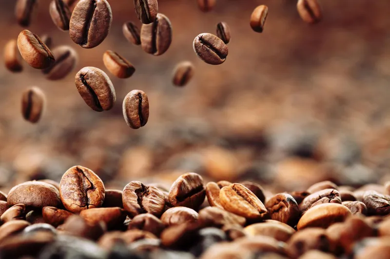 Coffee beans falling onto a pile of coffee beans